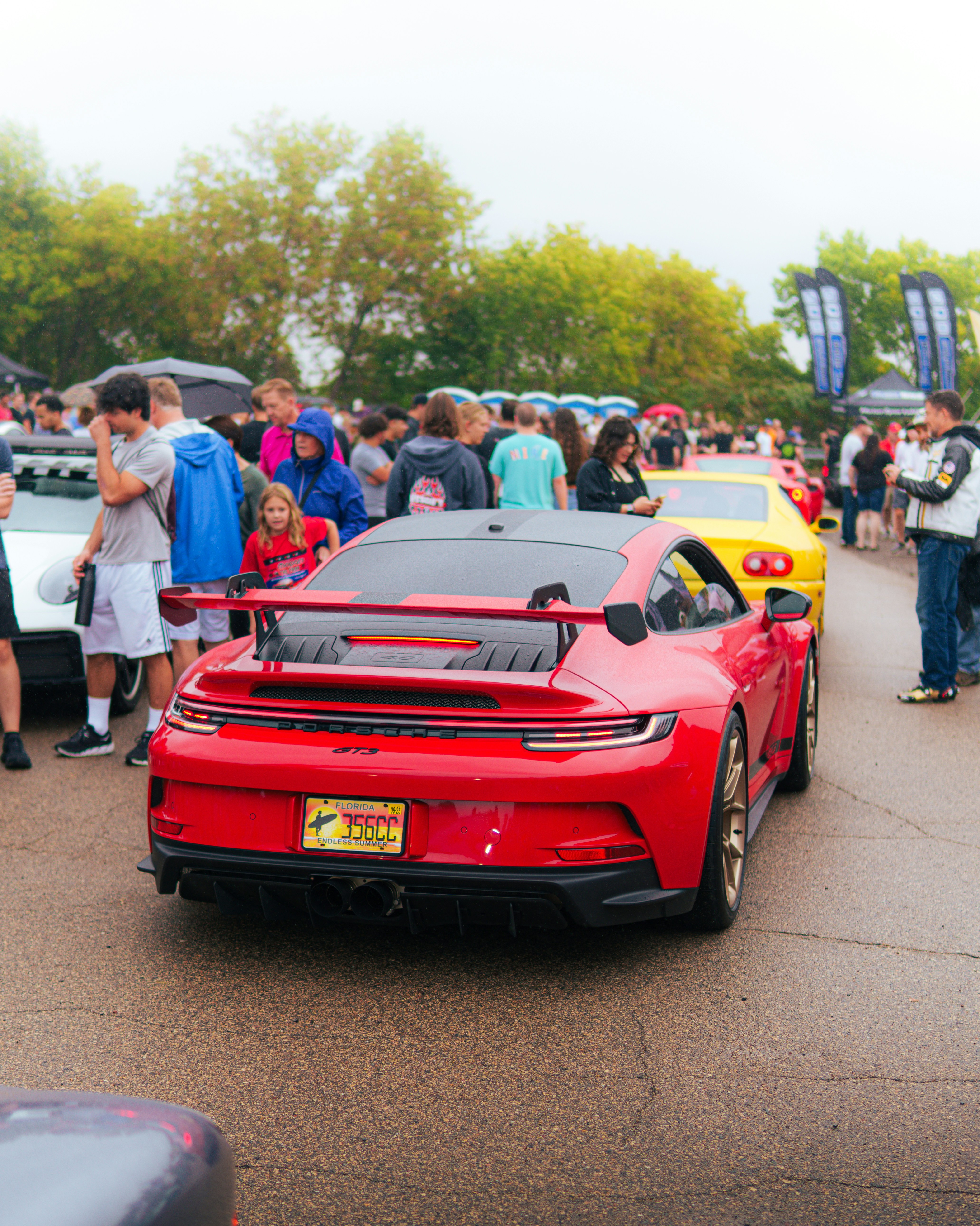 A group of people standing around a red sports car