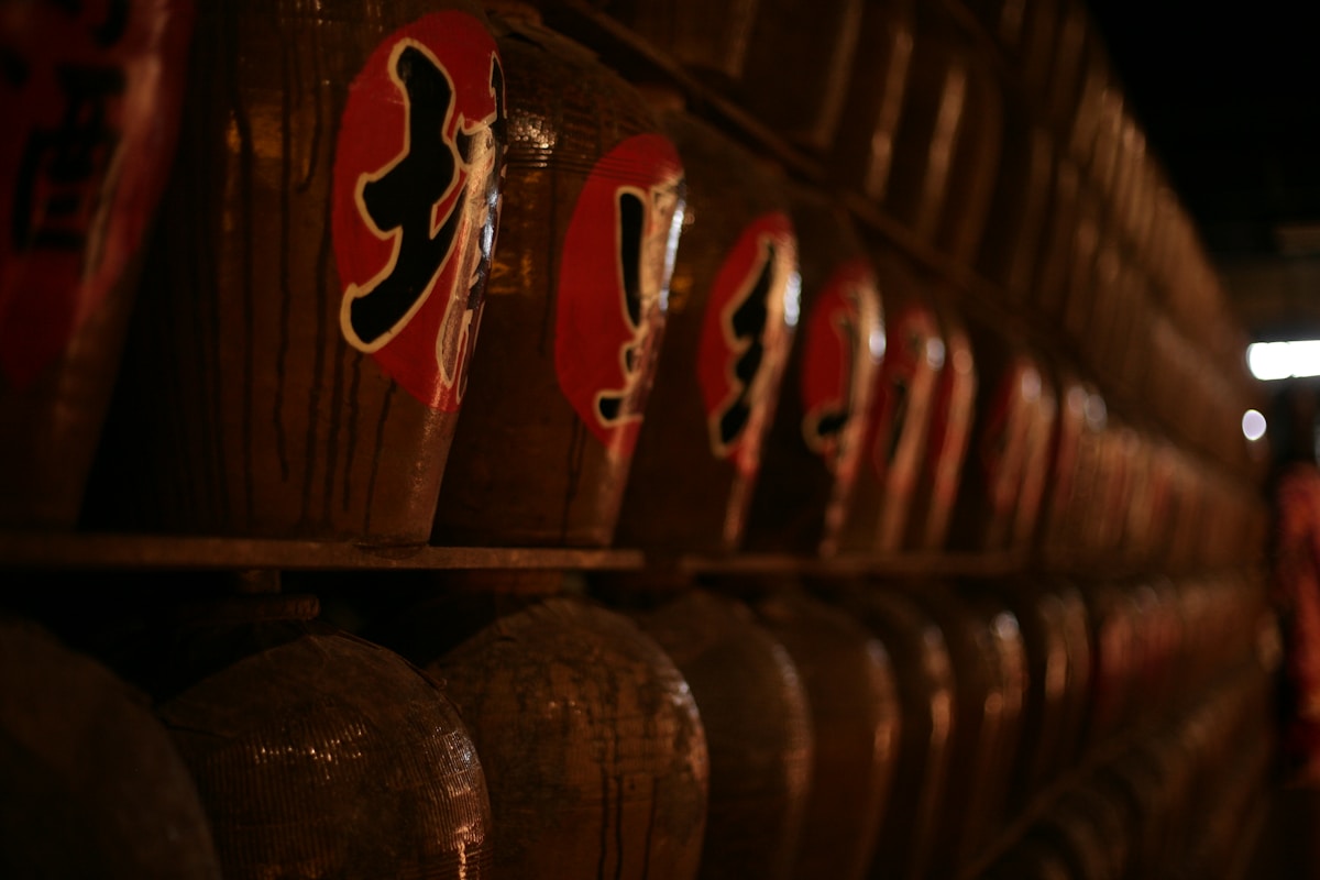 Japanese barrels with kanji calligraphy, warm light on aged wood