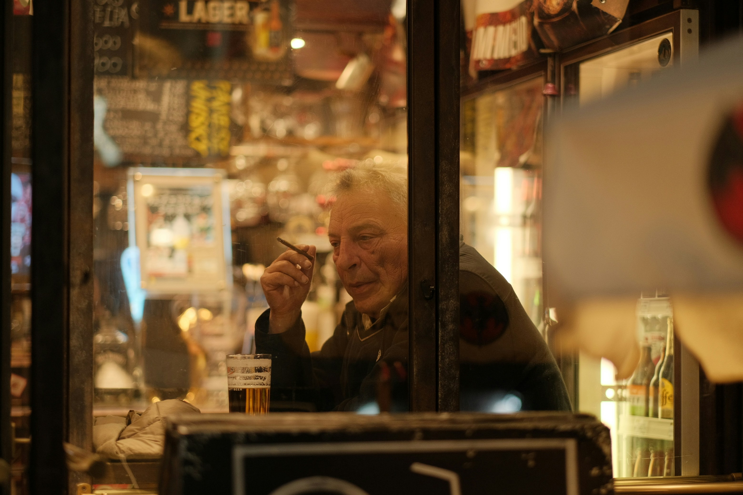 Man at a pub table seen through a window