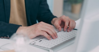 A person typing on a keyboard at a desk