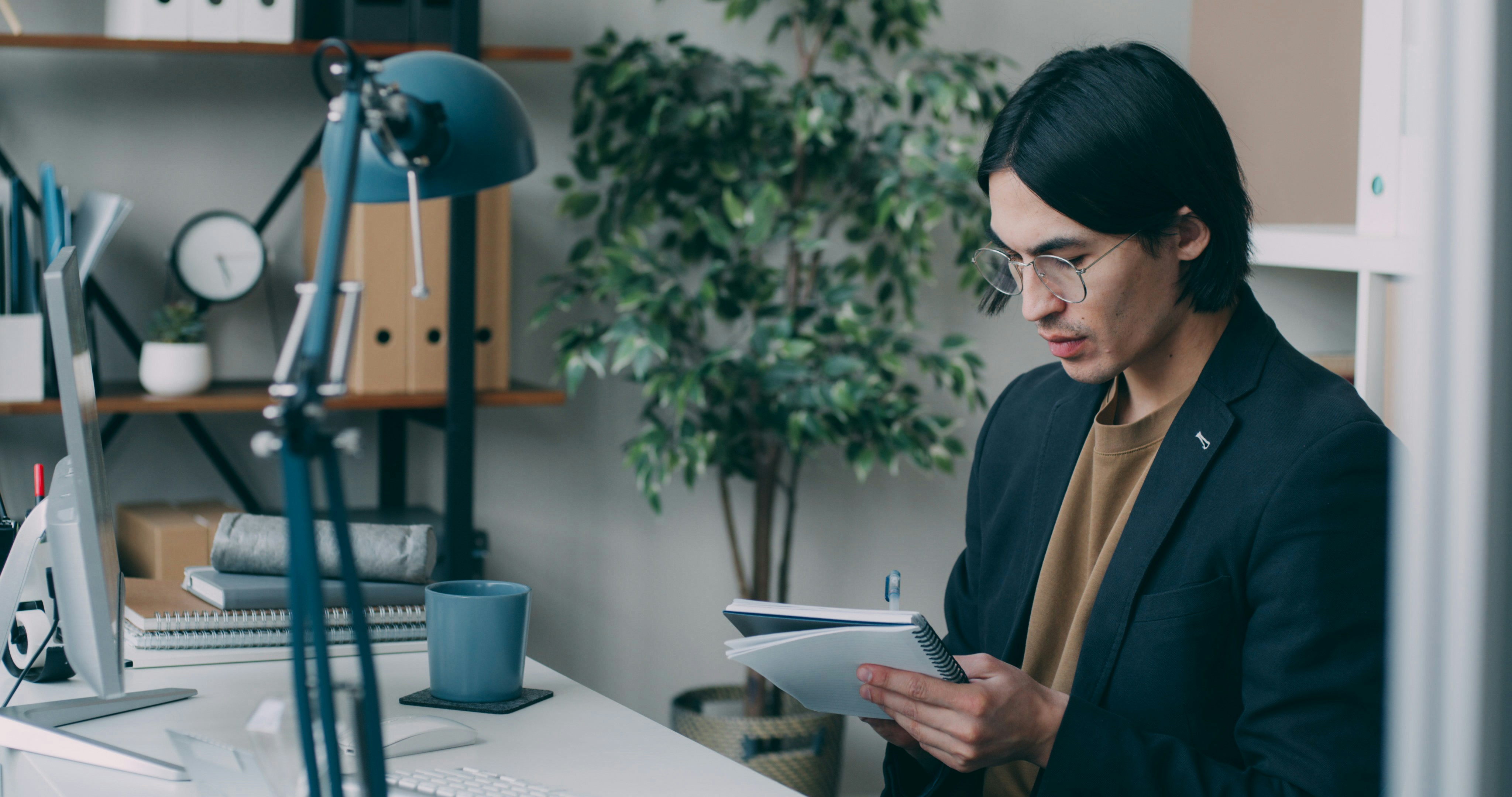A man standing in front of a desk holding a piece of paper