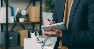 A man in a suit writing on a clipboard