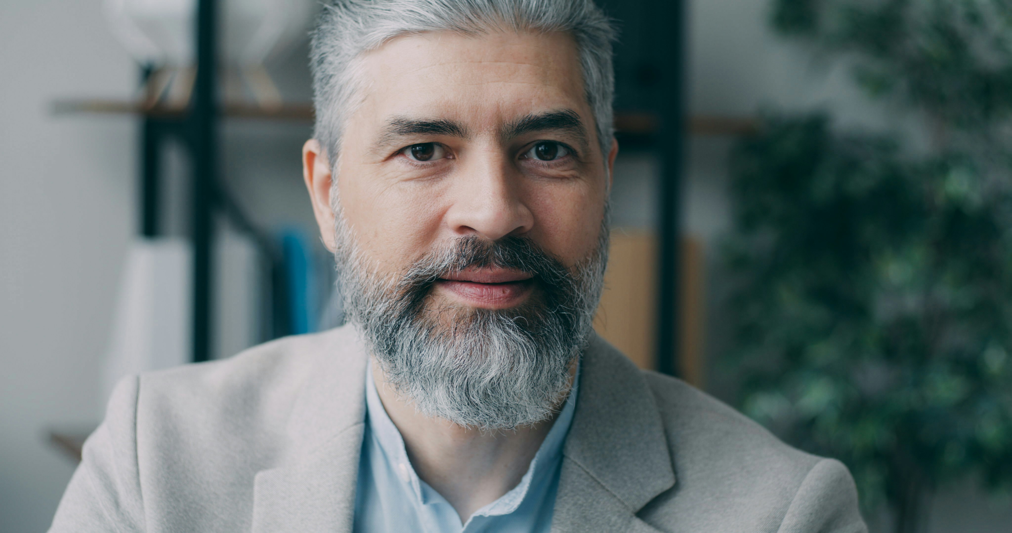 A man with grey hair and beard wearing a suit