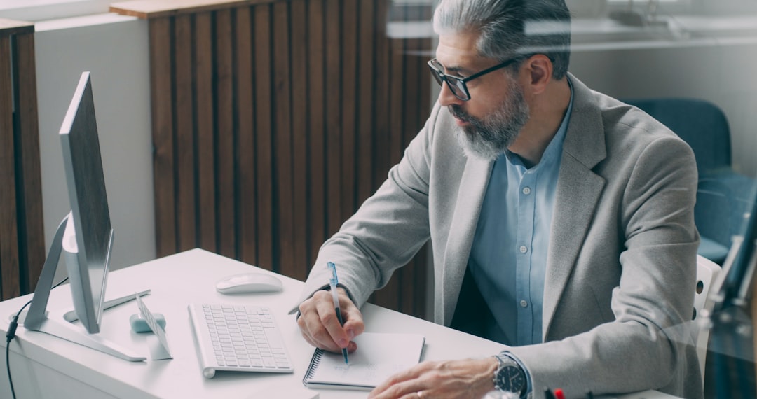 A man sitting at a desk writing on a piece of paper, Experienced businessman doing research