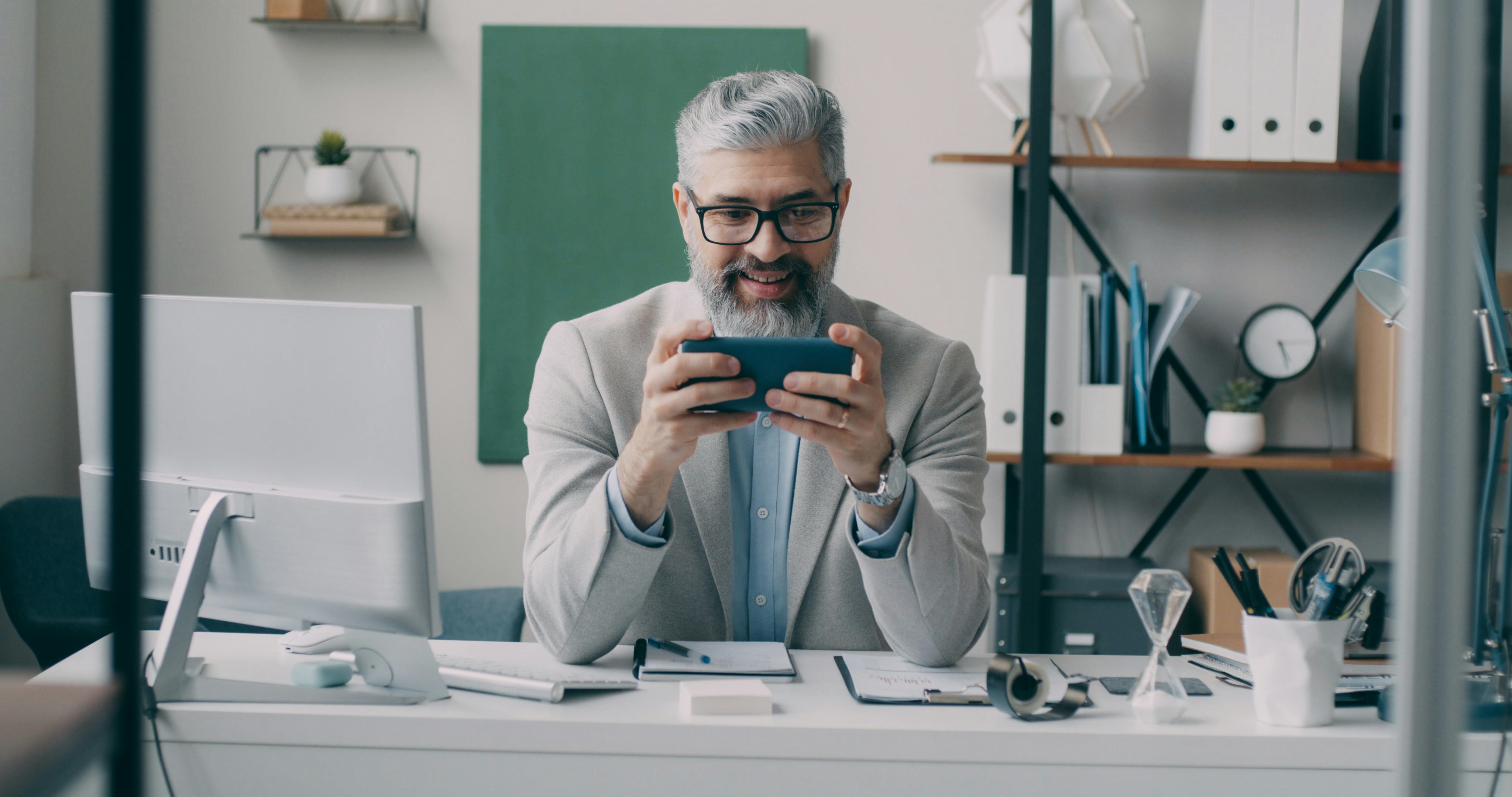 A man sitting at a desk using a cell phone