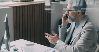 A man sitting at a desk talking on a cell phone