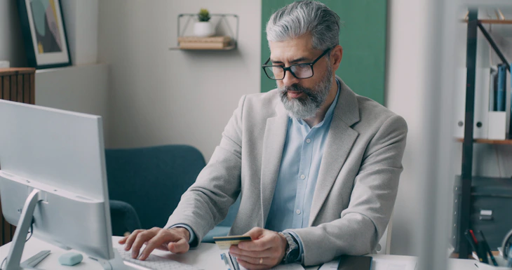 A man sitting at a desk using a laptop computer
