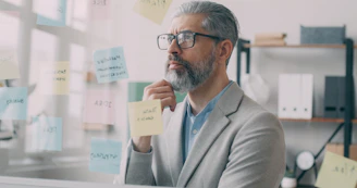 A man in a suit and glasses holding a piece of paper