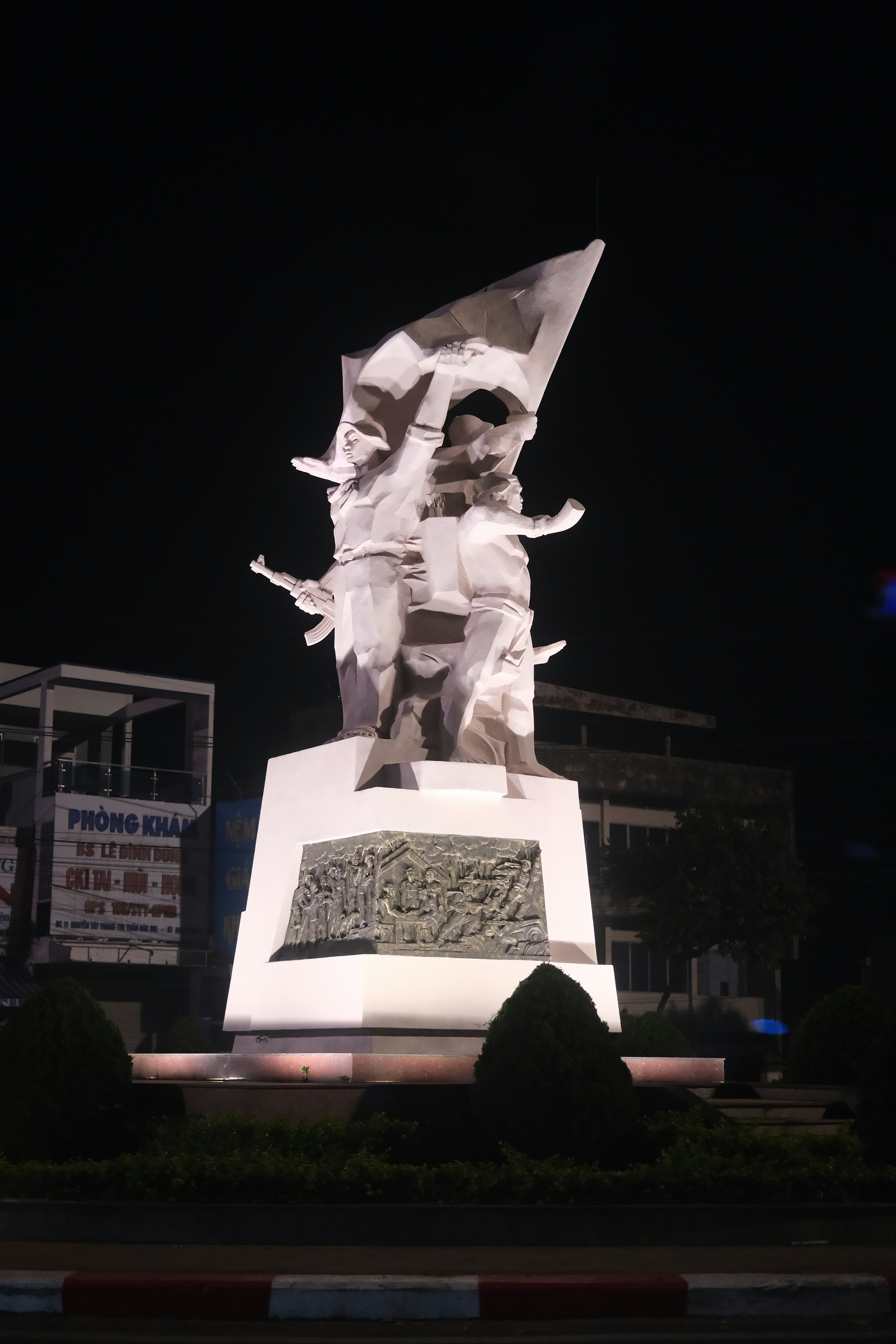 Patung seorang pria memegang bendera di depan sebuah gedung