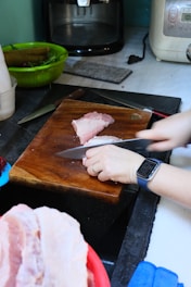 A person cutting meat on a cutting board