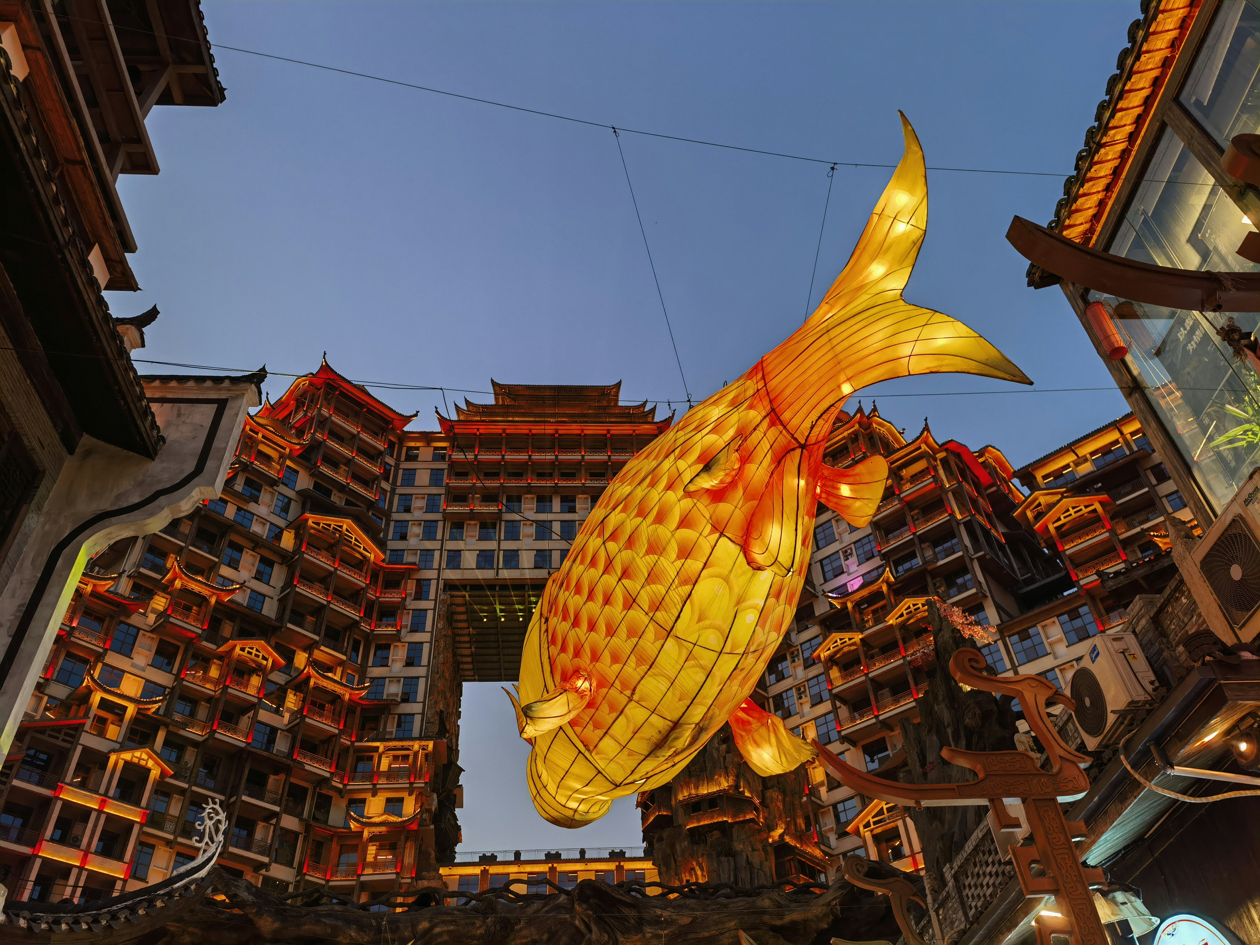 A gold fish statue hanging from the side of a building