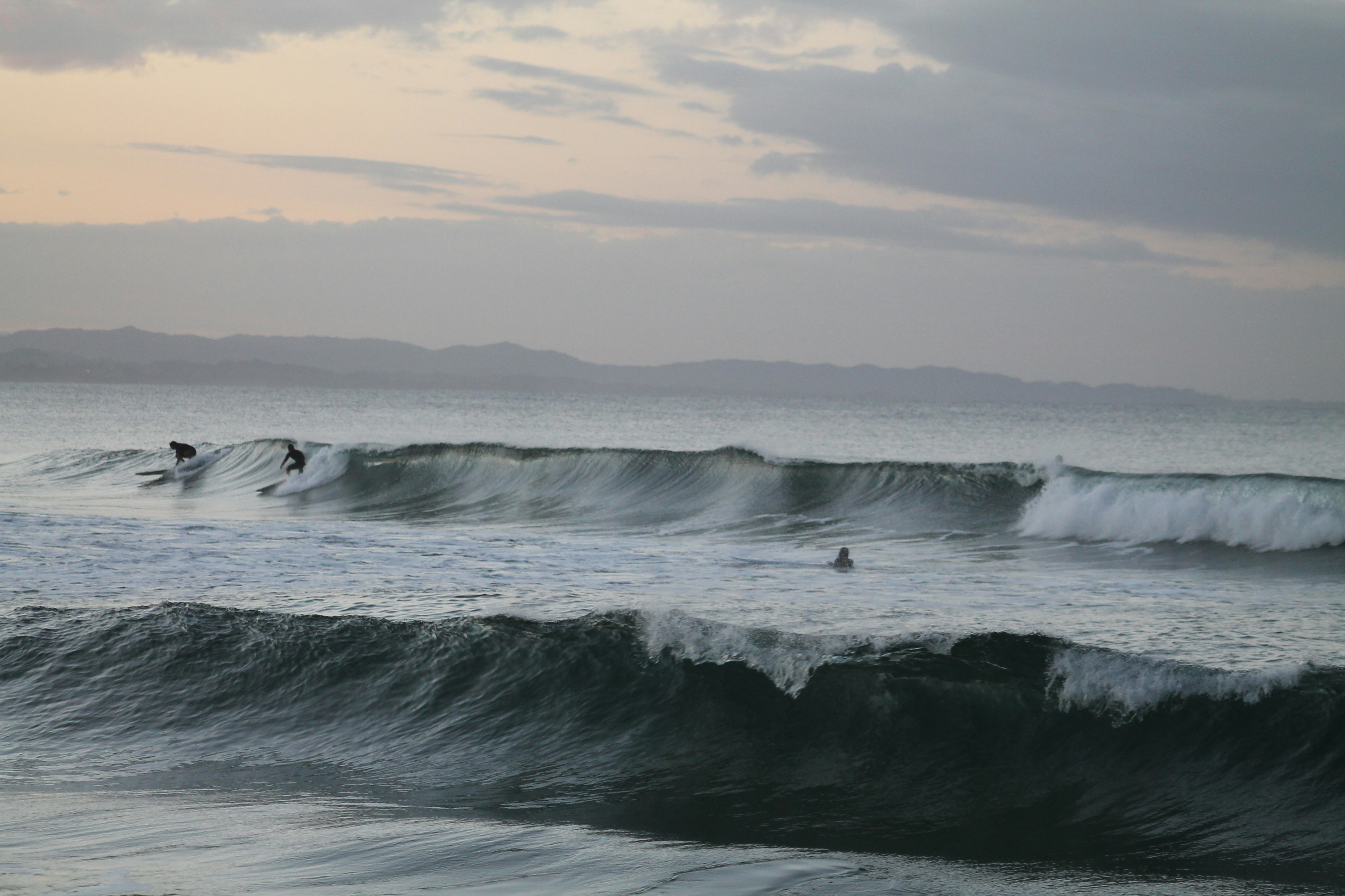 A group of people riding waves on top of surfboards