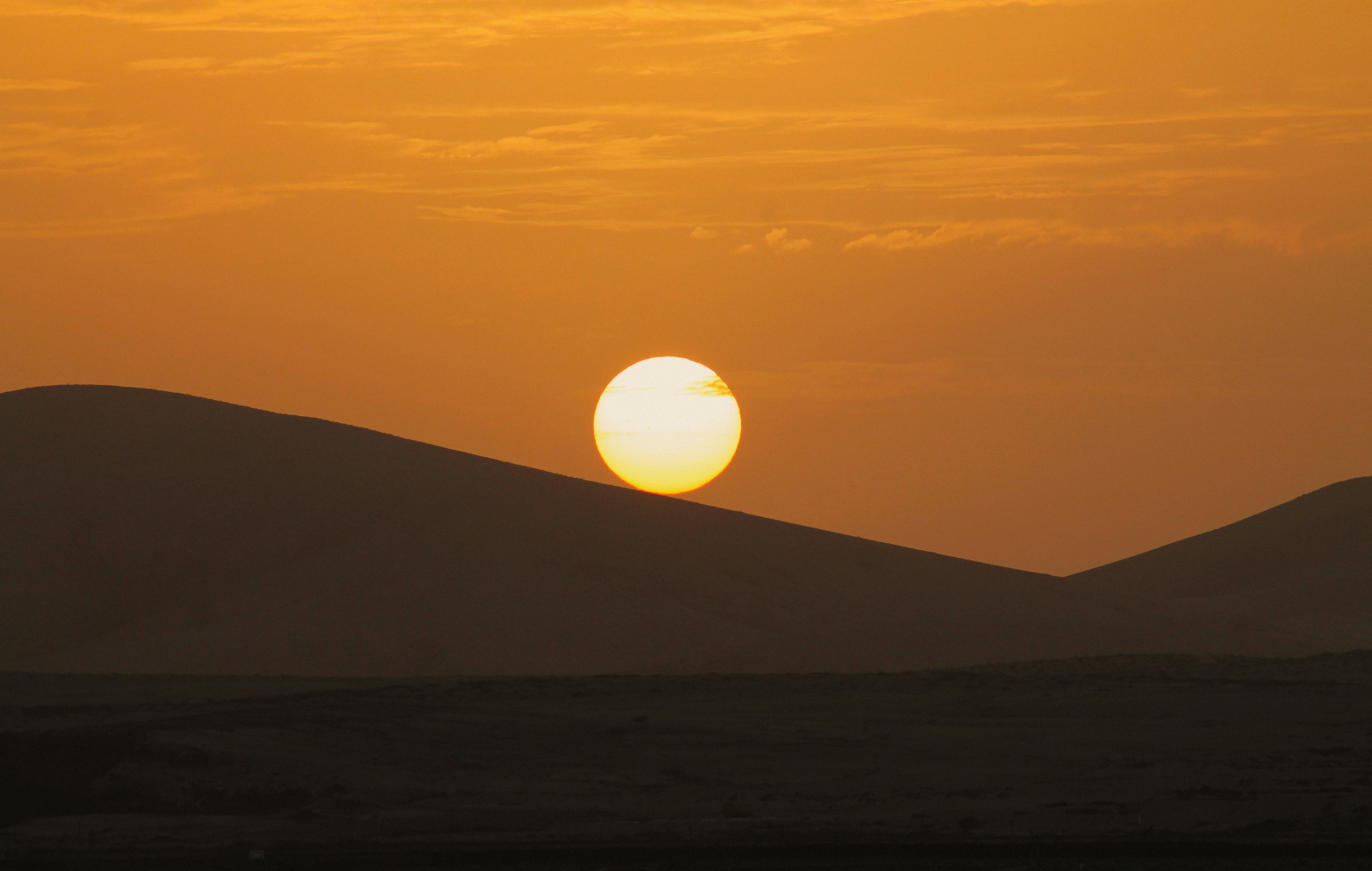 The sun is setting over the hills in the distance