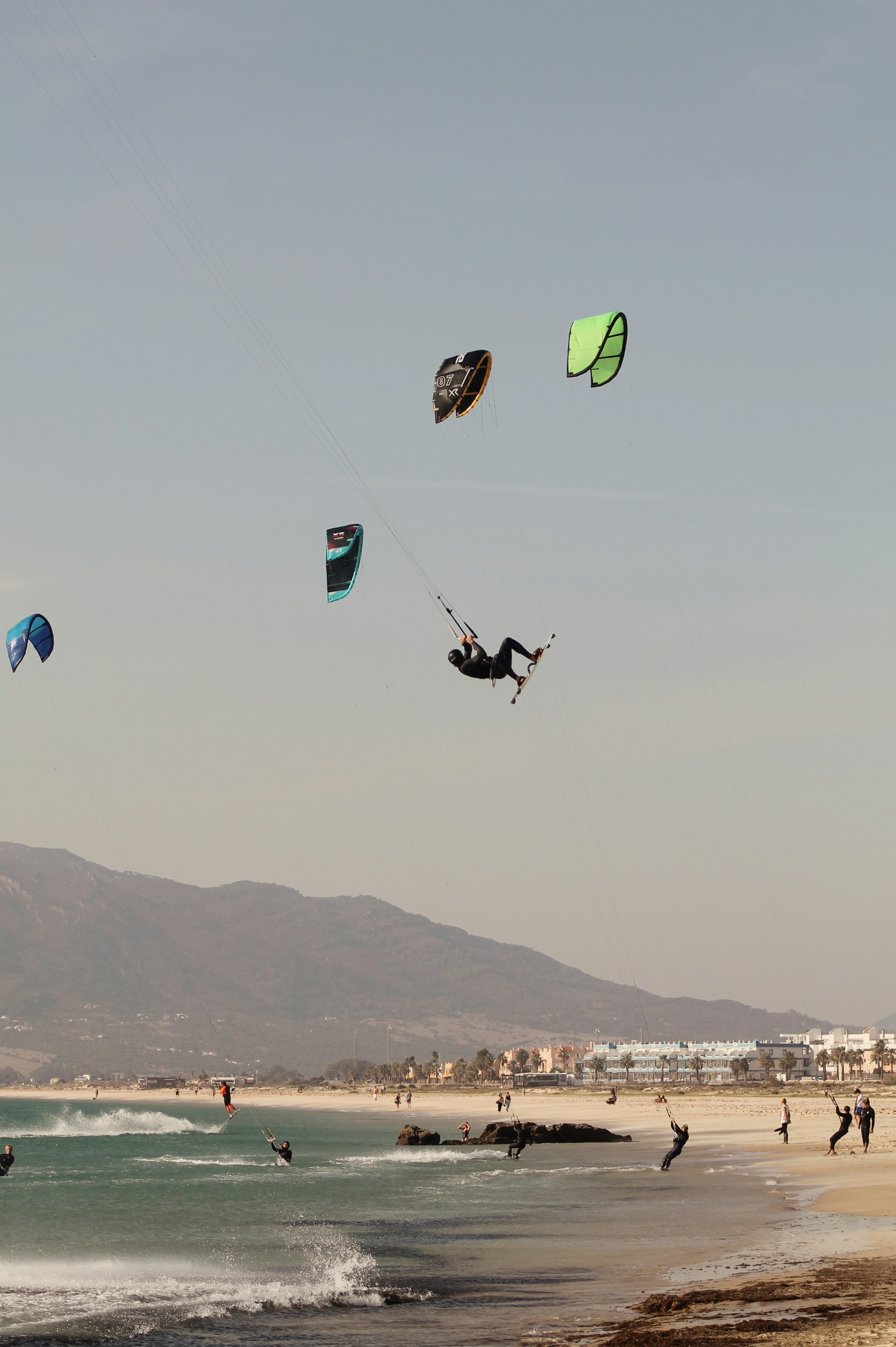 A group of people flying kites on top of a sandy beach