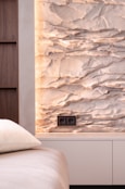 A bedroom with a white bed and a stone wall