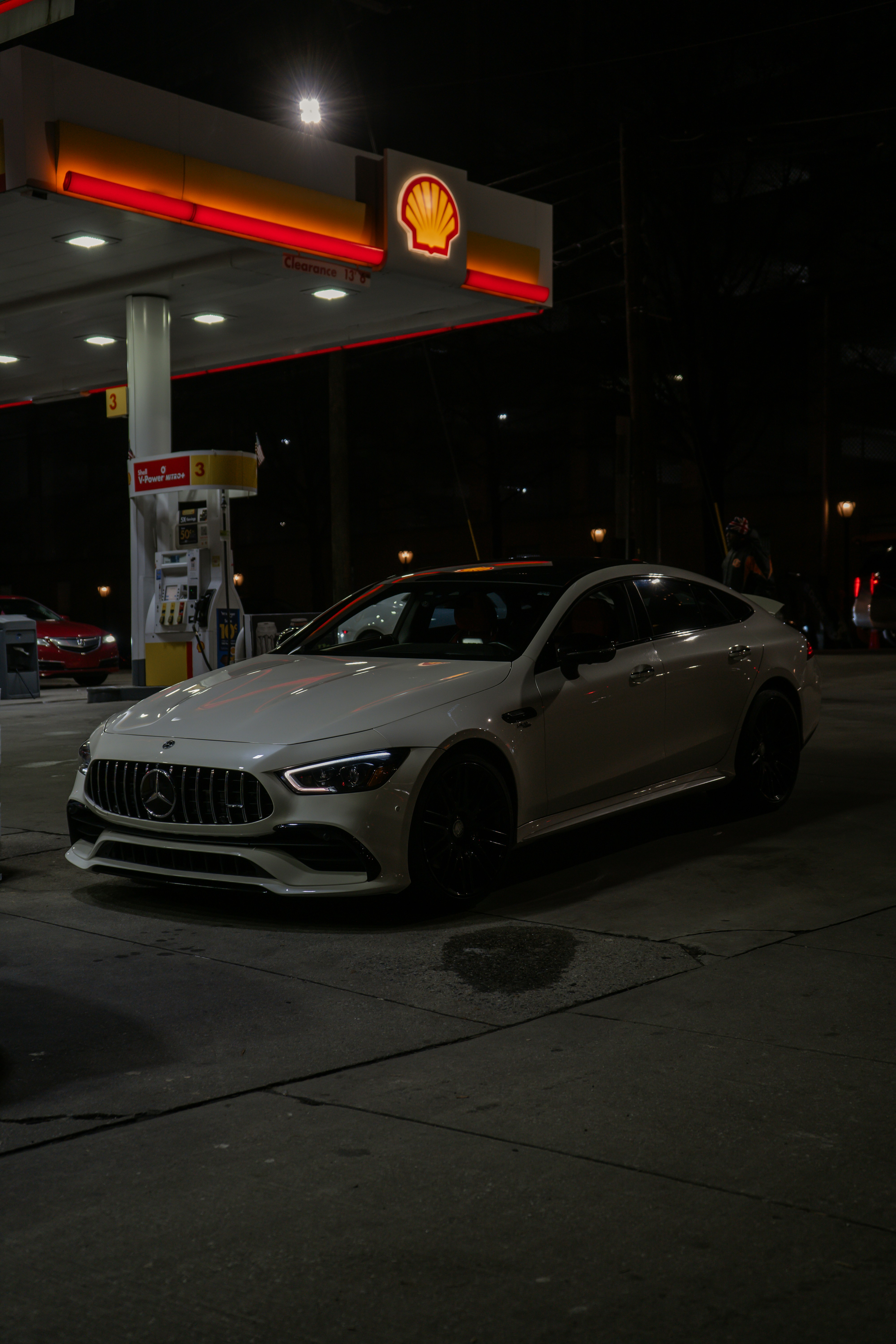 A white car parked in front of a gas station