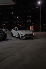 Two cars parked in a parking lot at night
