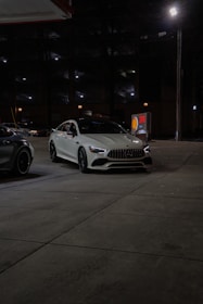 Two cars parked in a parking lot at night