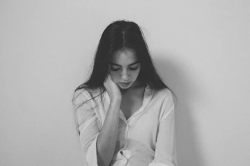 A woman sitting on a bed with her hands on her head