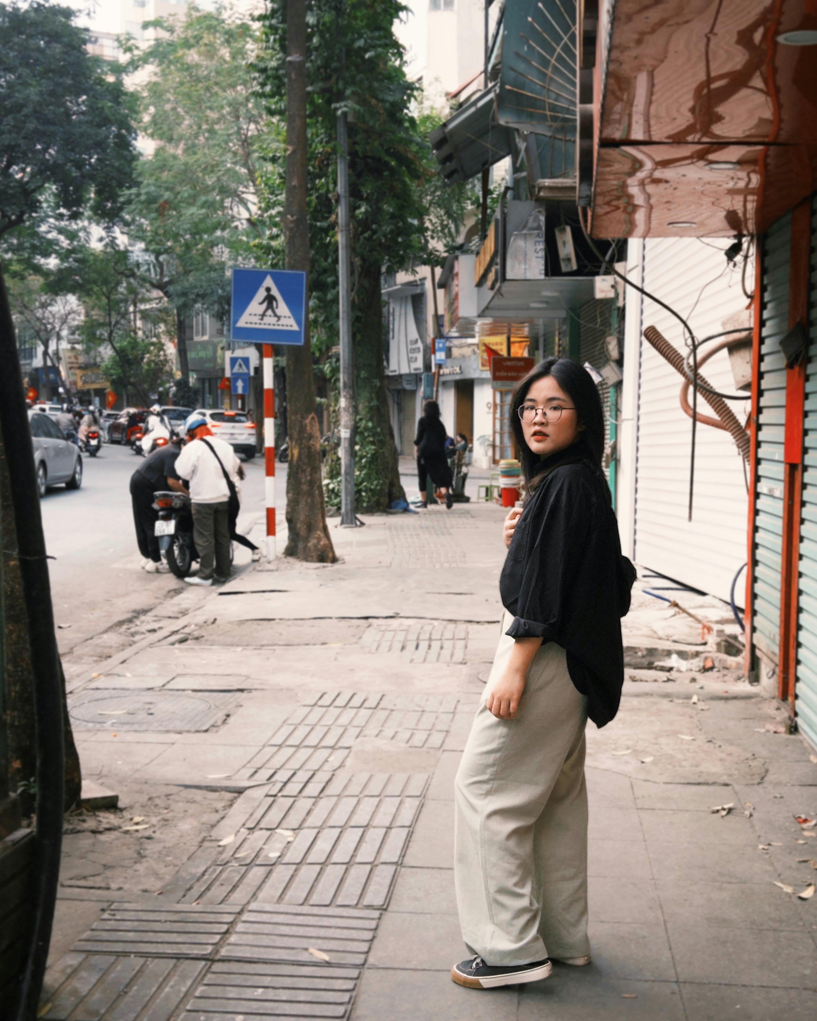 A woman standing on a sidewalk next to a building