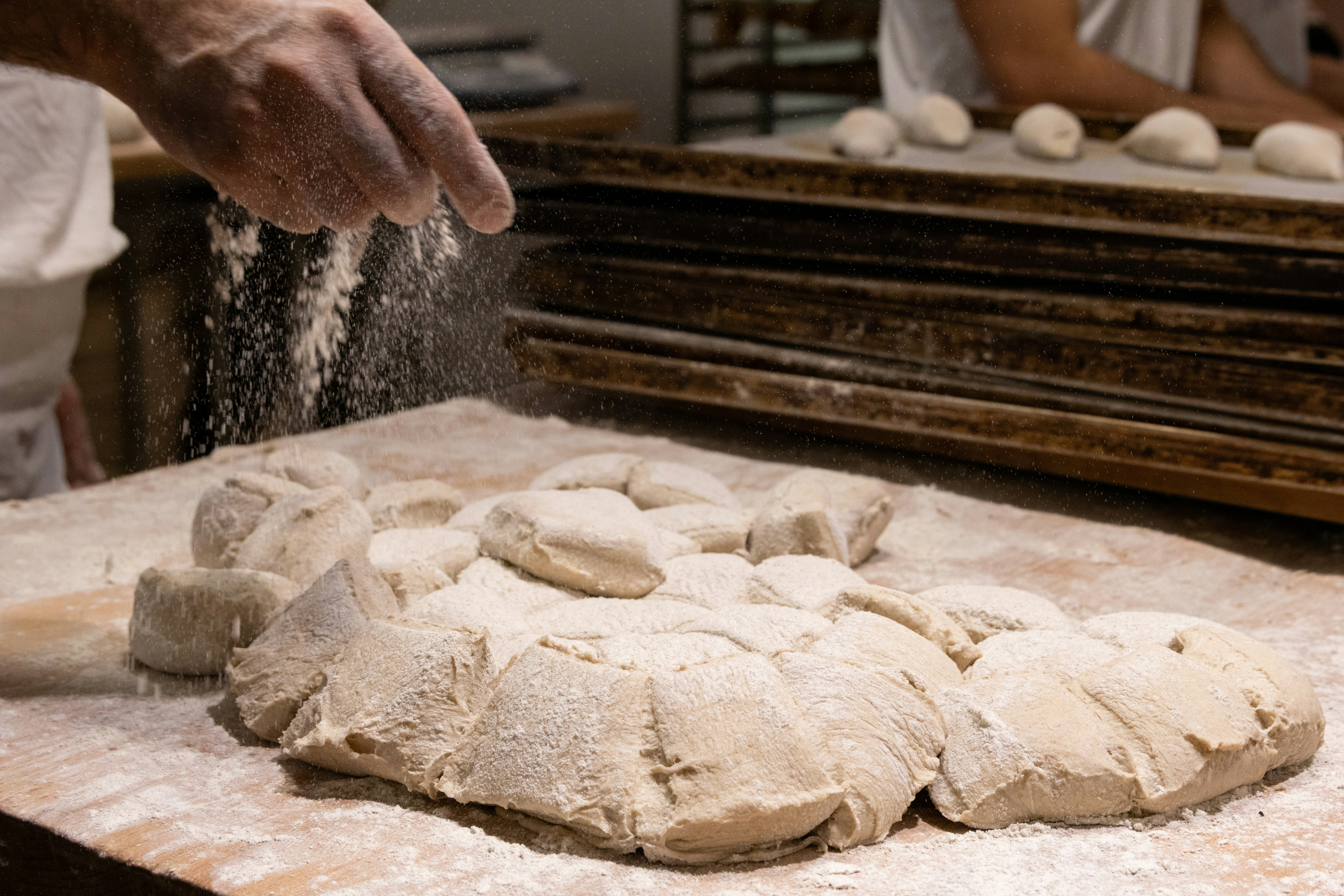 A person is sprinkling flour on a doughnut