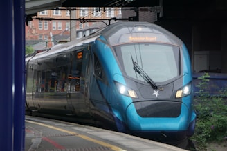 A blue train traveling down train tracks next to a train station