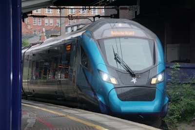 A blue train traveling down train tracks next to a train station