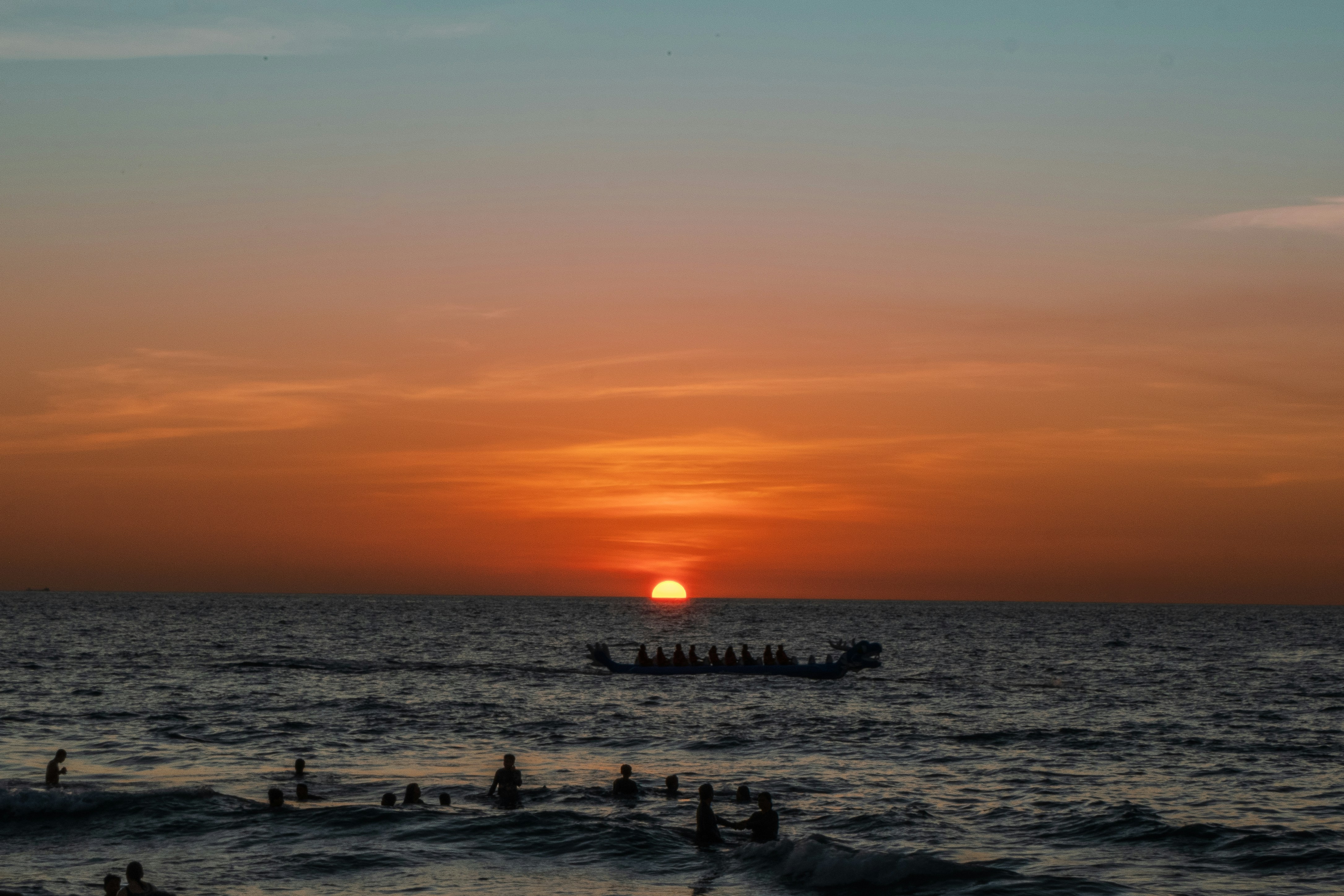A sunset over a body of water with a boat in the distance