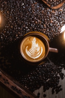 Cup of coffee with late art surrounded by roasted beans - Avventura Coffee Collections