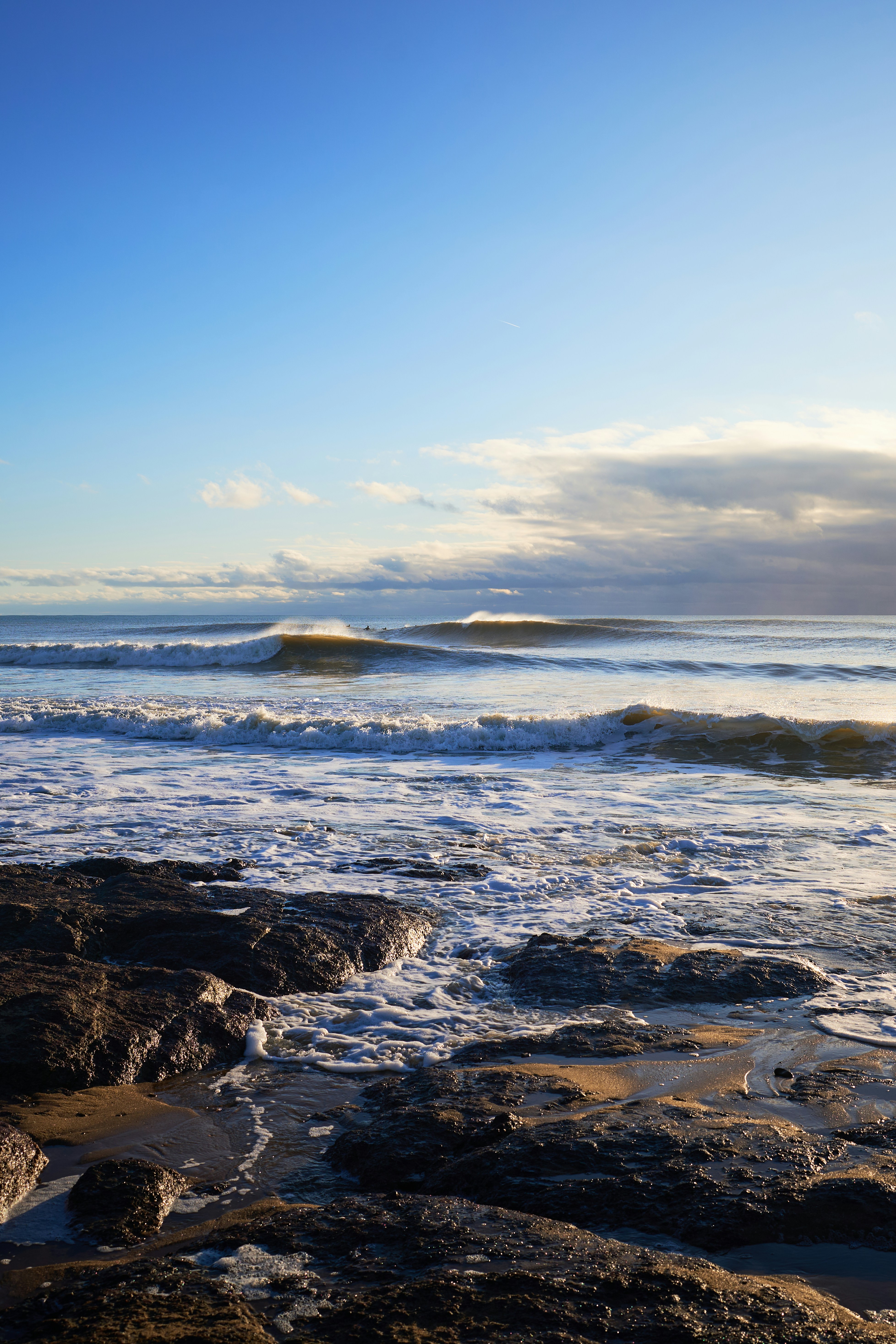 A person standing on a rocky beach with a surfboard