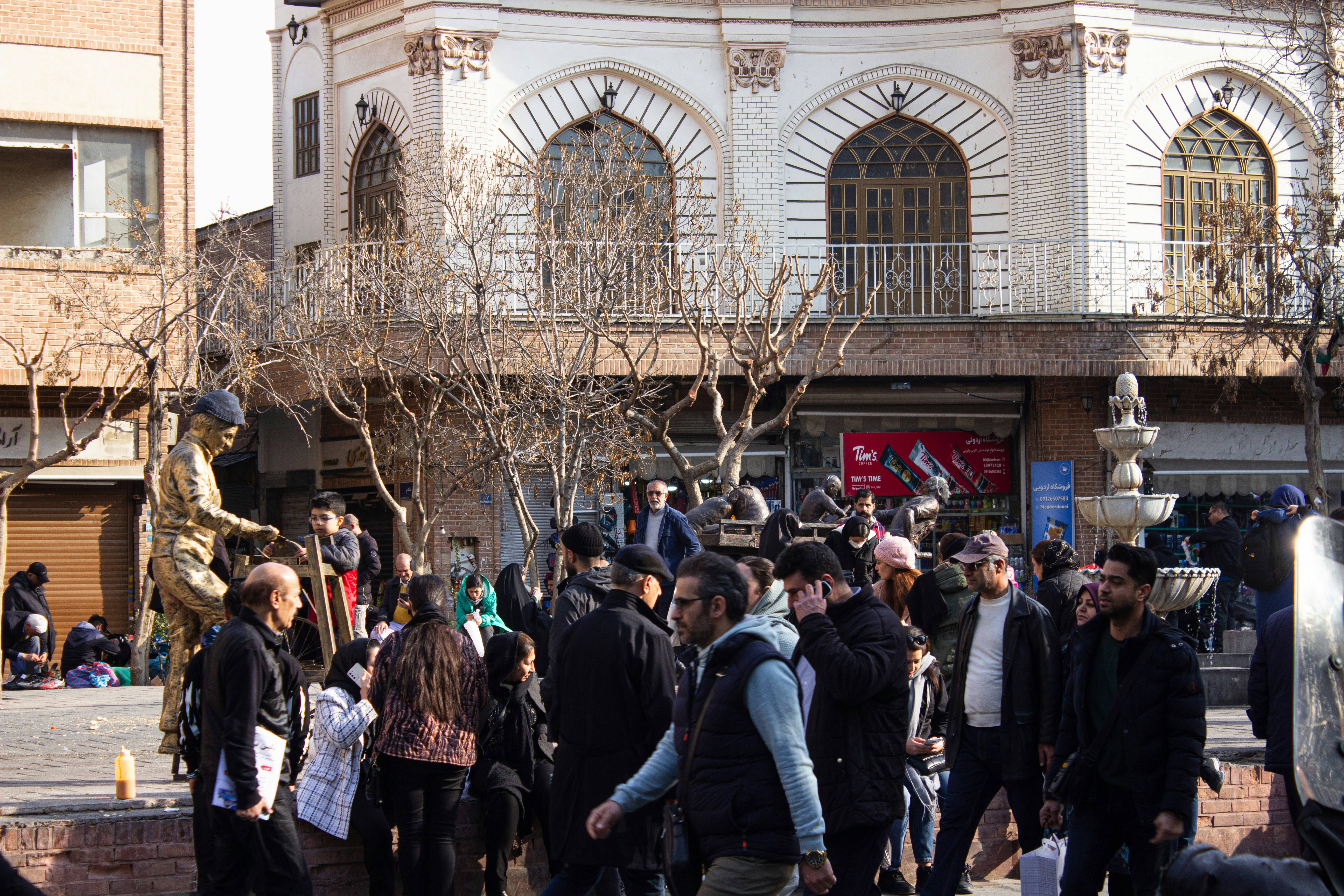 A crowd of people walking down a street next to tall buildings