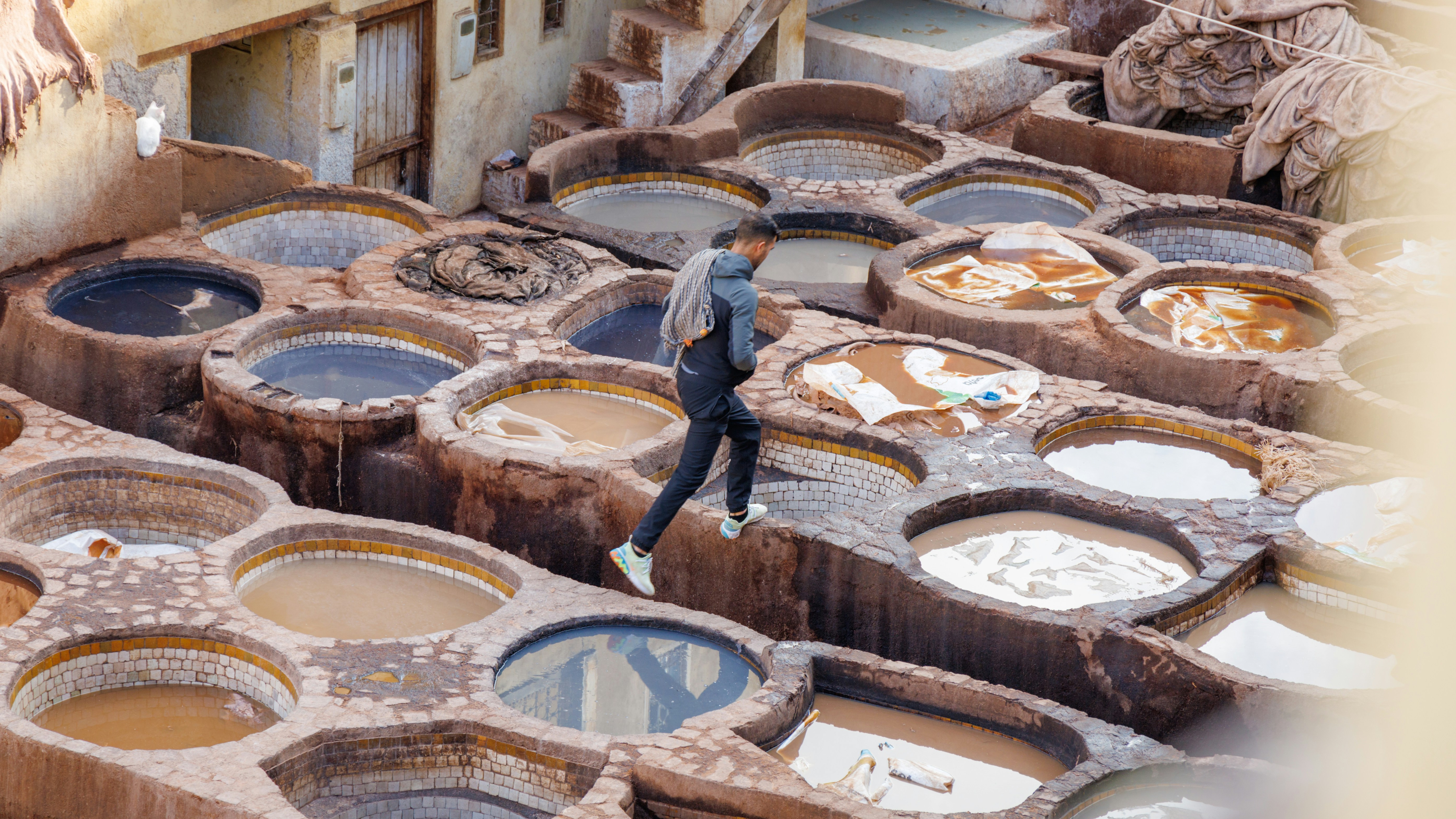 A worker hopping on top of tanneries in Fez, Morocco.