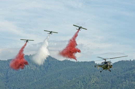 A group of planes flying through the air with red smoke coming out of them