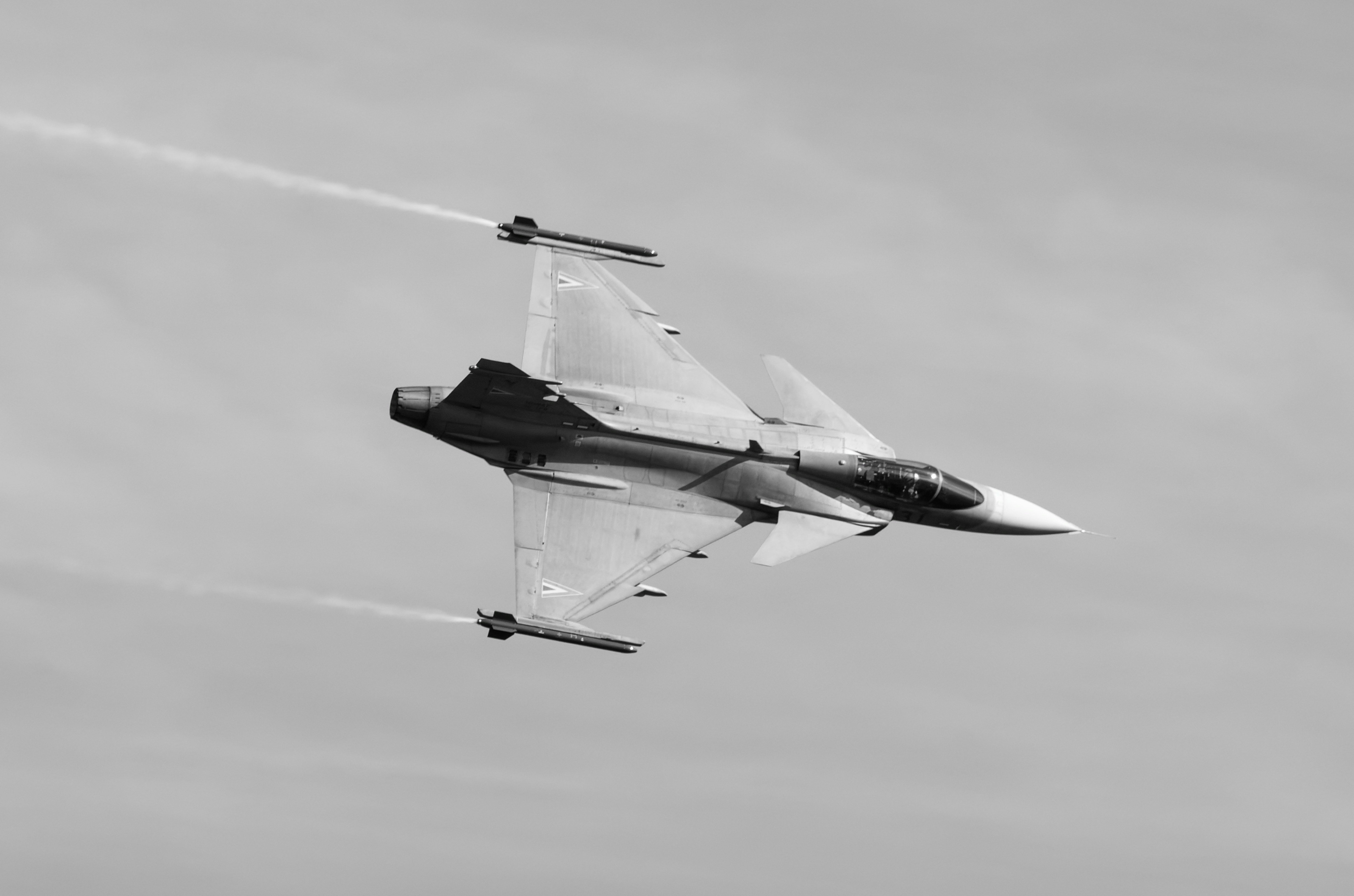 A fighter jet flying through a cloudy sky, Gripen during a turn.