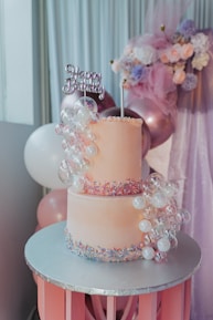 A pink and white cake sitting on top of a table
