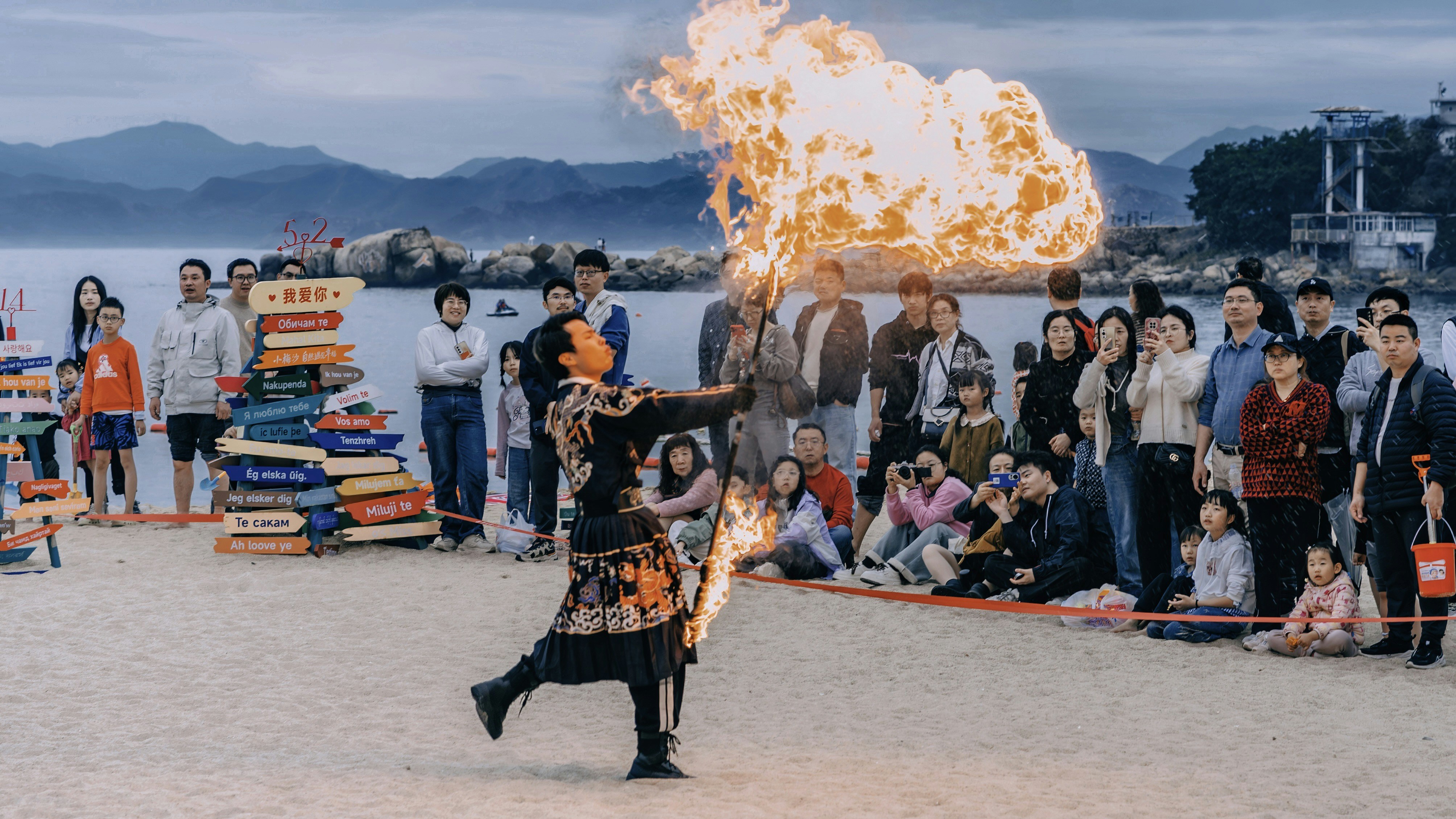 A man holding a fire stick on top of a beach