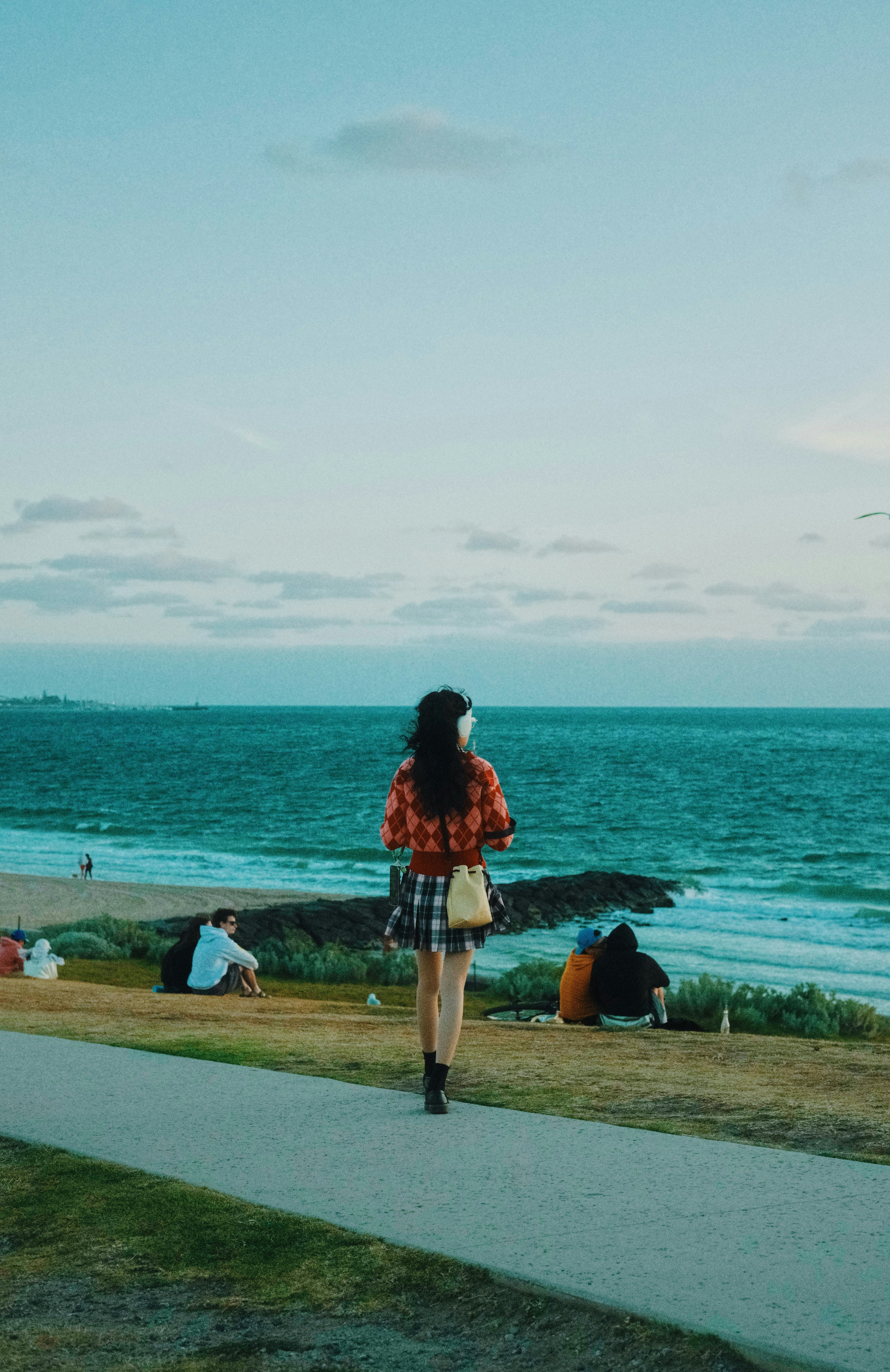 A woman walking down a sidewalk next to the ocean