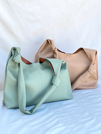 Two purses sitting side by side on a bed