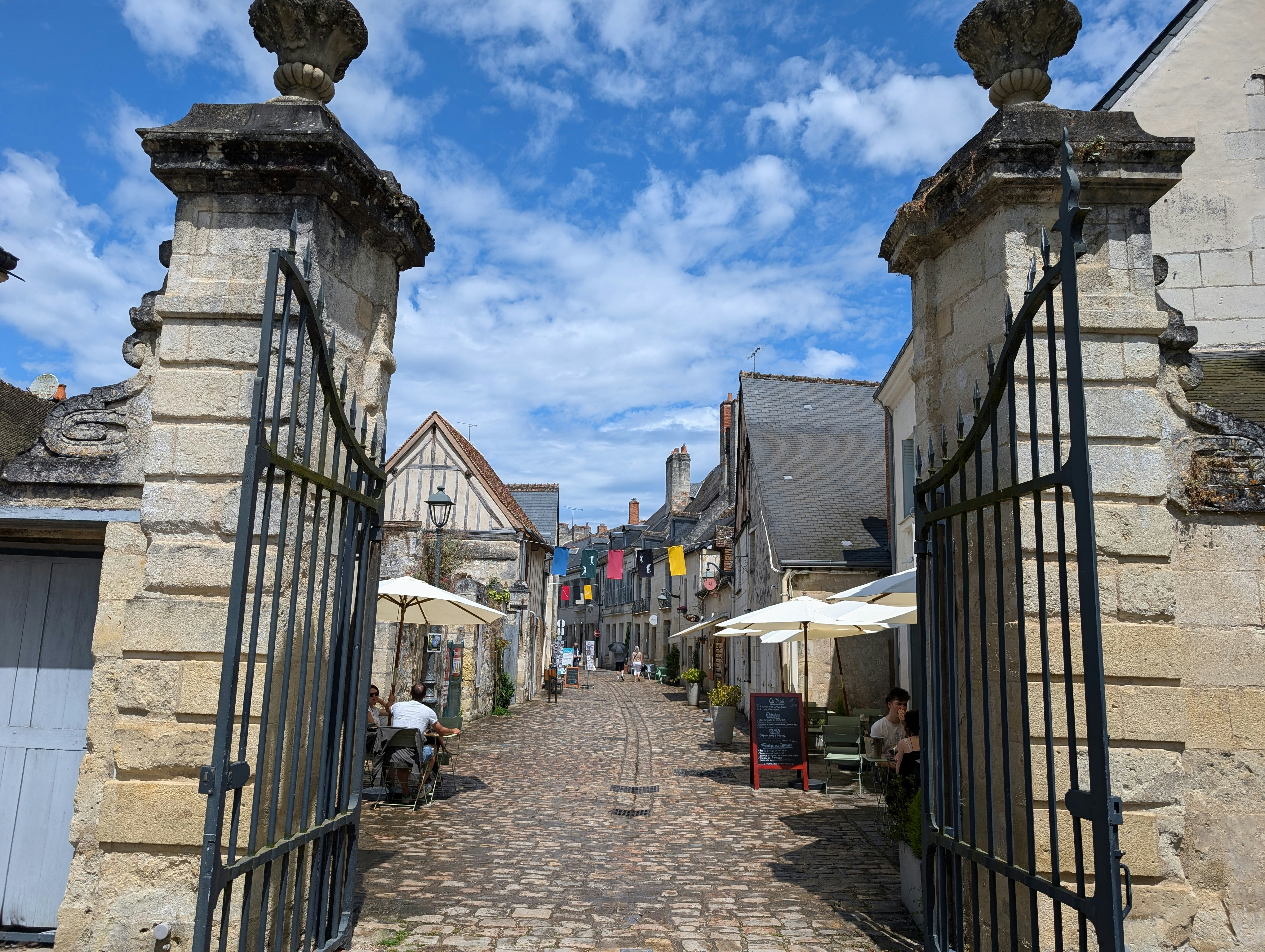 A stone street with a gate and umbrellas