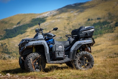 A four - wheeler parked in a field with mountains in the background
