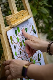 A person is painting a tree on a canvas