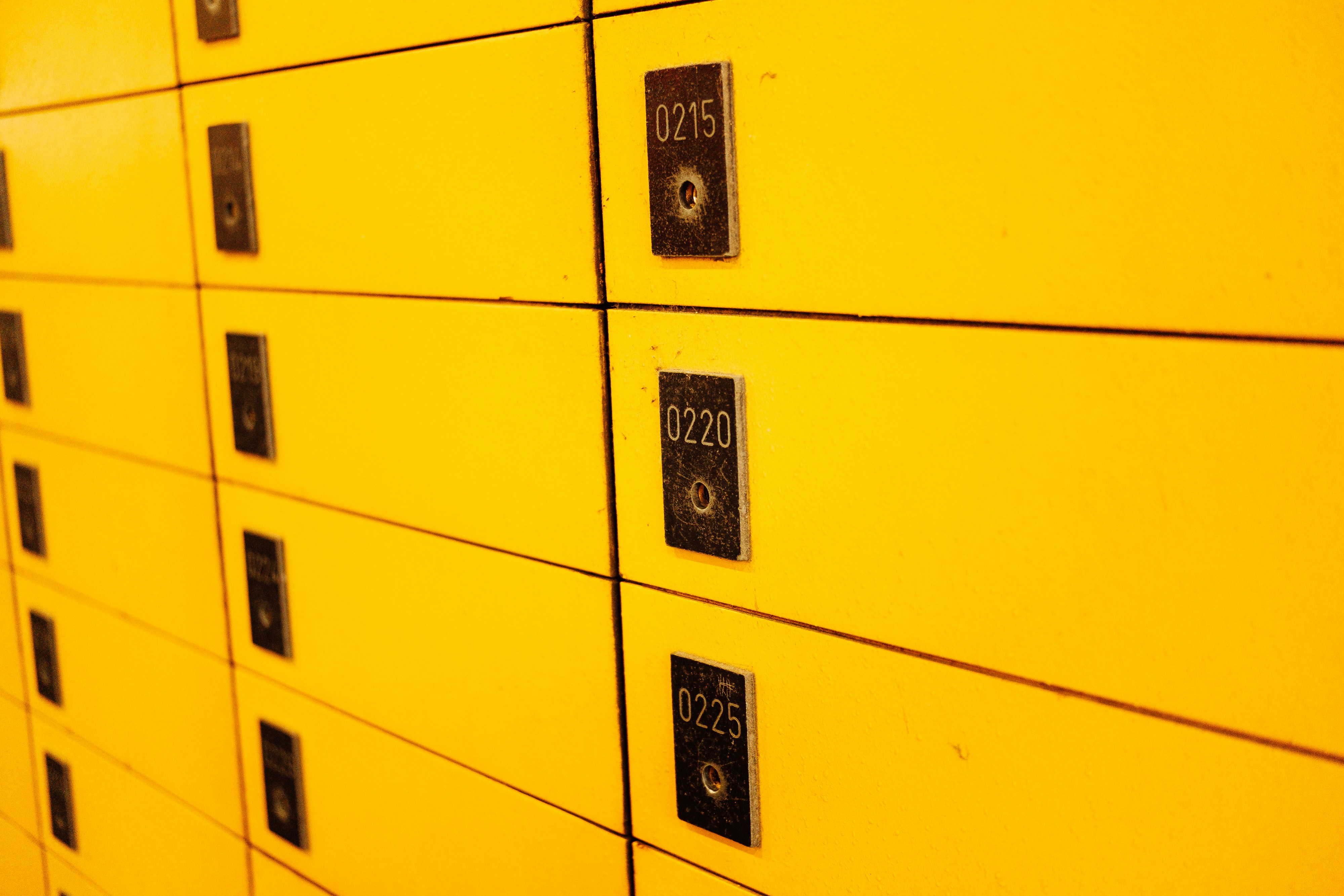 A row of yellow lockers with black labels on them