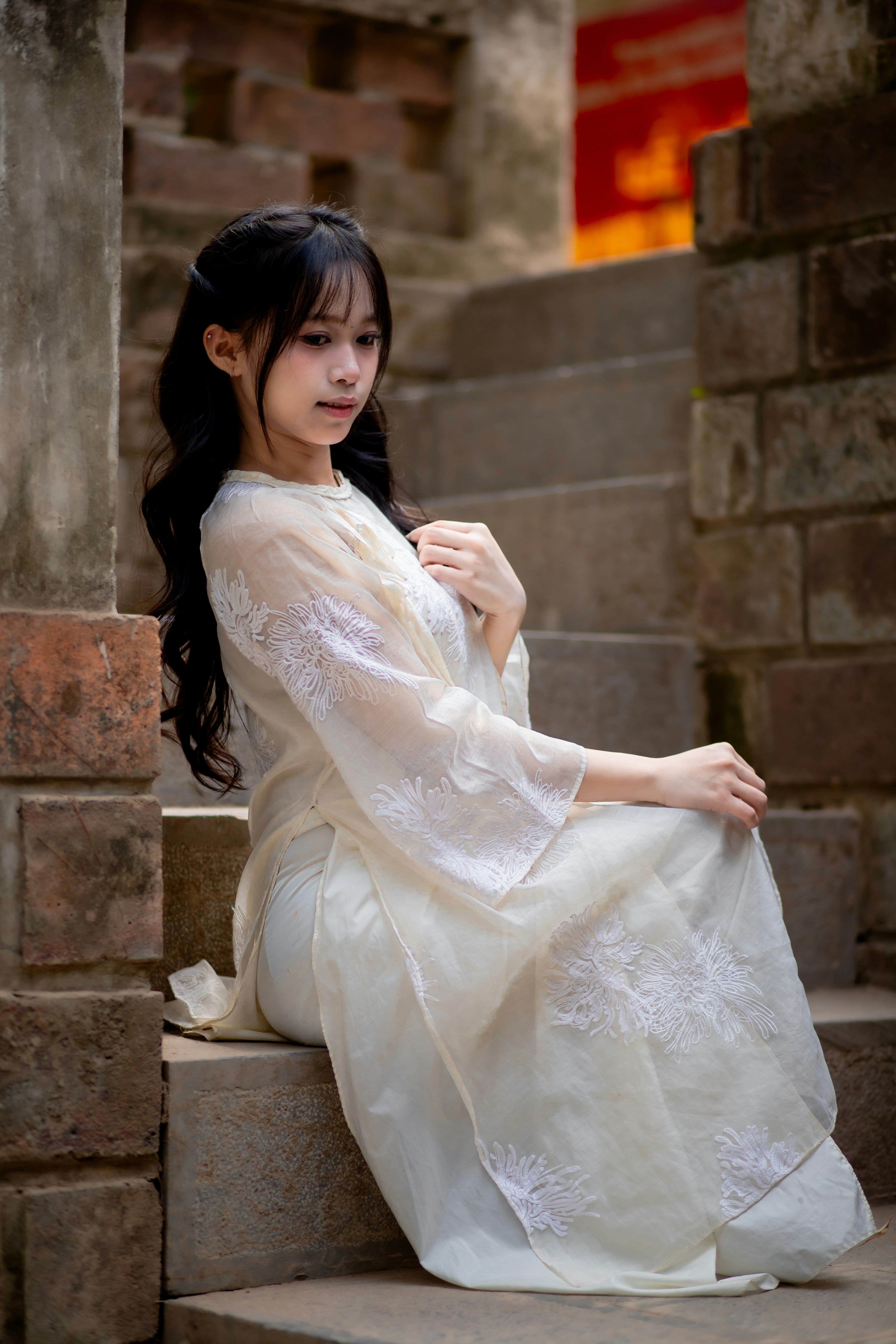 A woman in a white dress sitting on steps