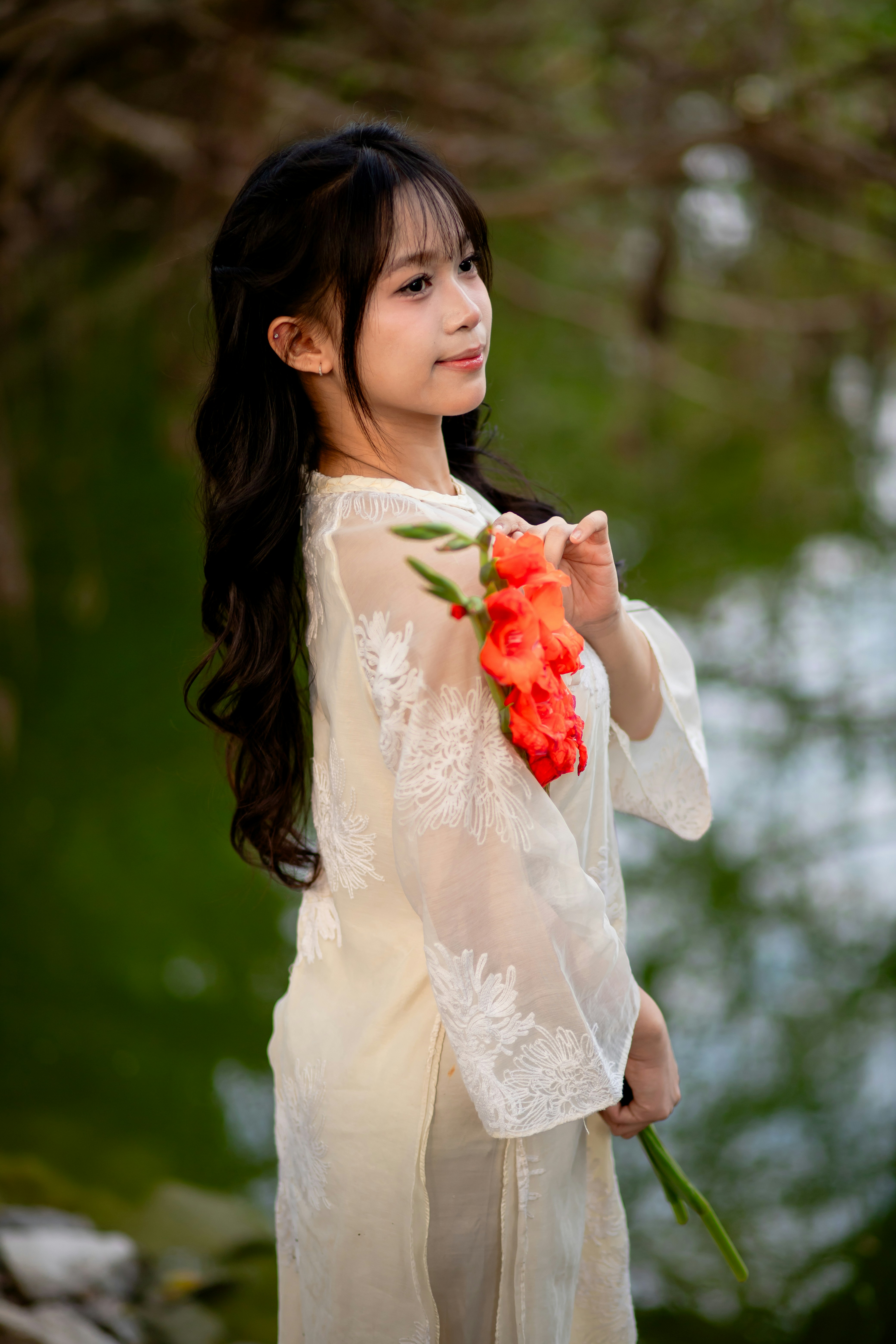 A girl in a white dress holding a flower