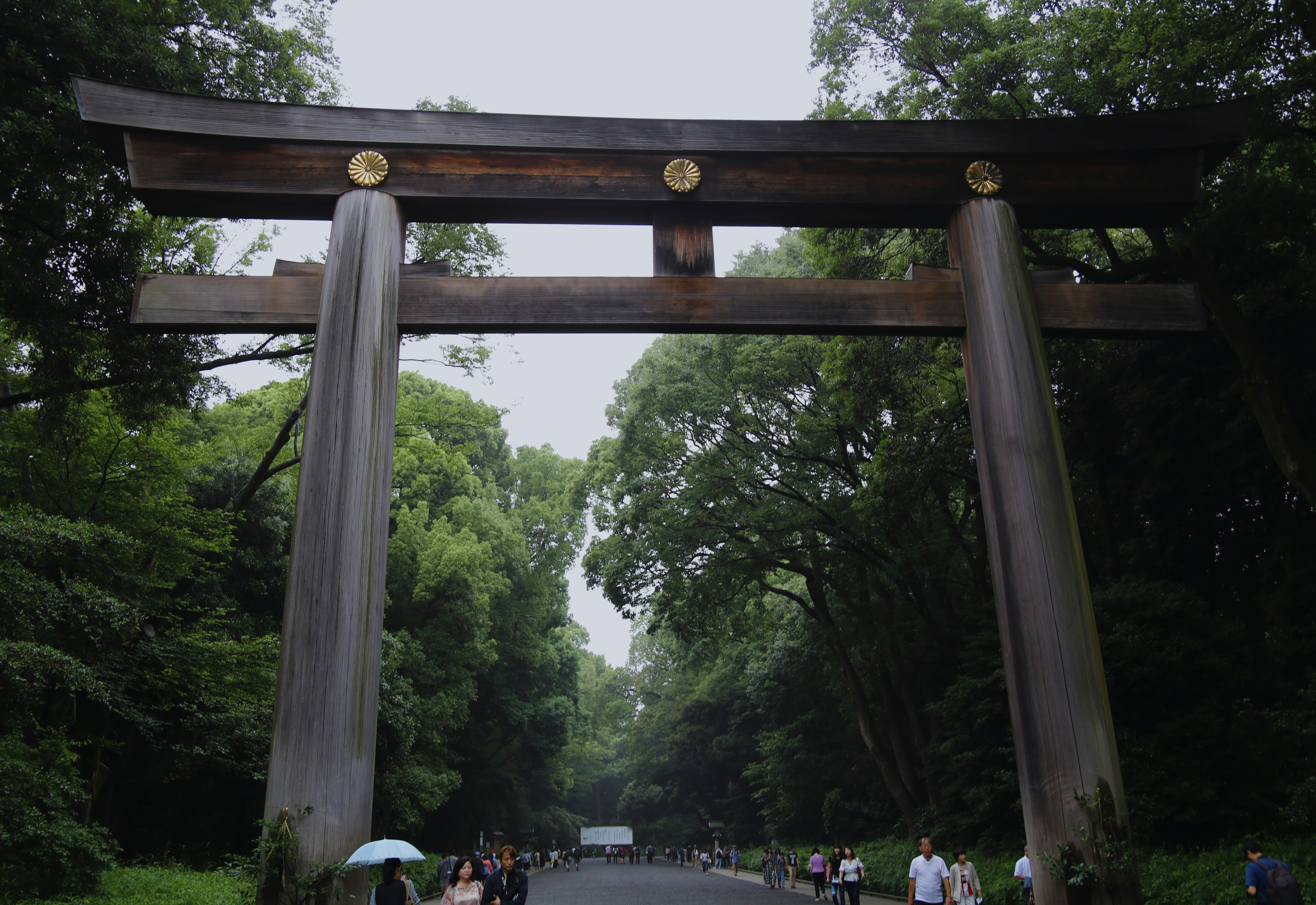 A group of people walking down a road under an arch