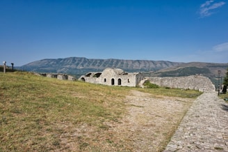 A stone building sitting on top of a lush green hillside