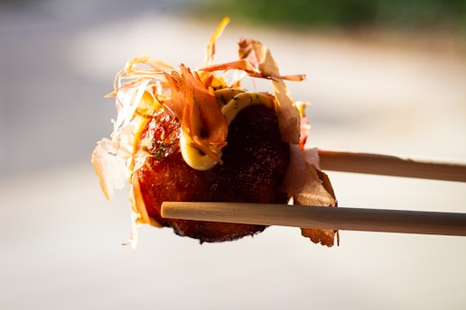 A person holding chopsticks with food on them