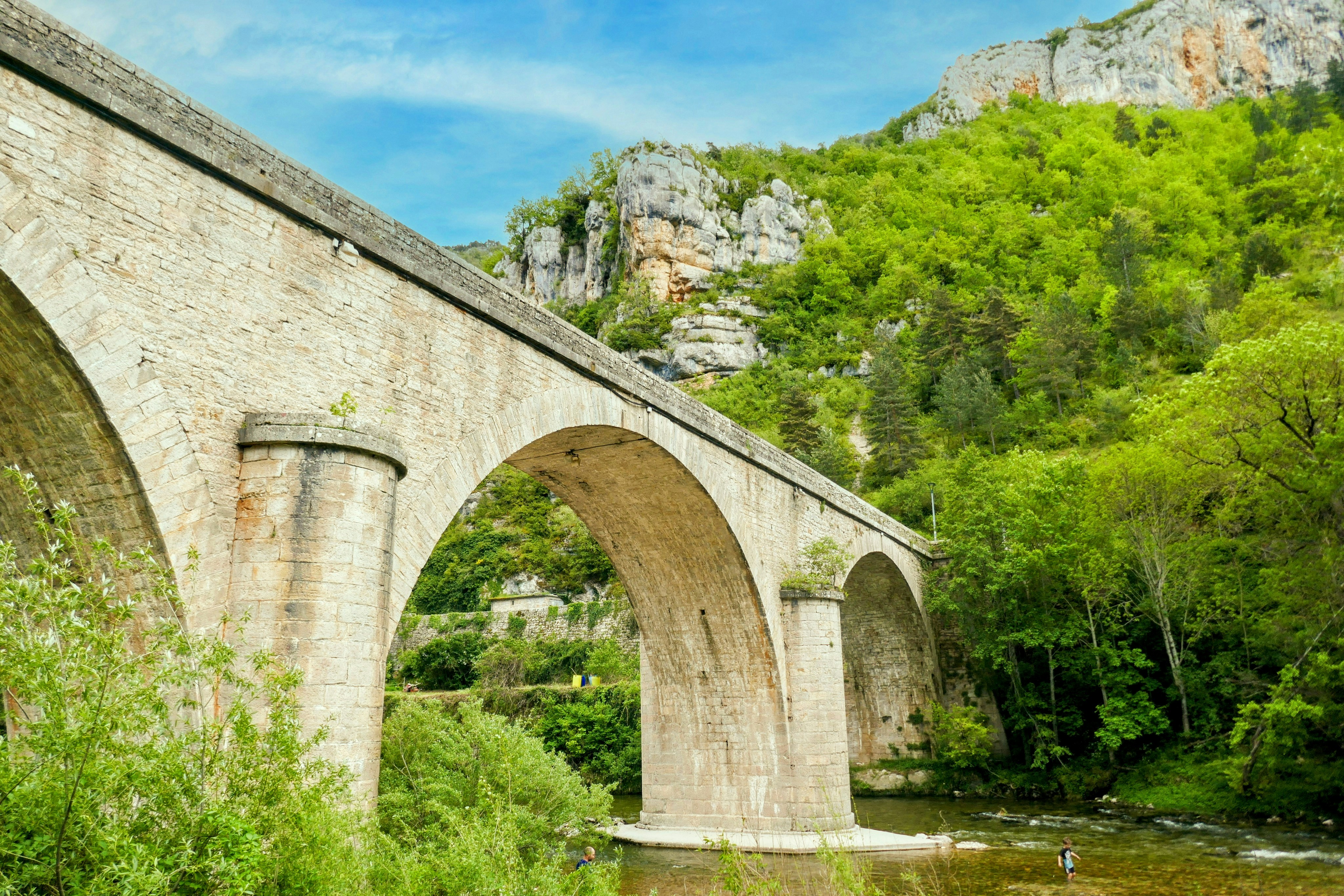 A stone bridge over a river surrounded by trees