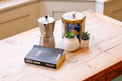 A kitchen counter with a book, coffee pot, and other items on it