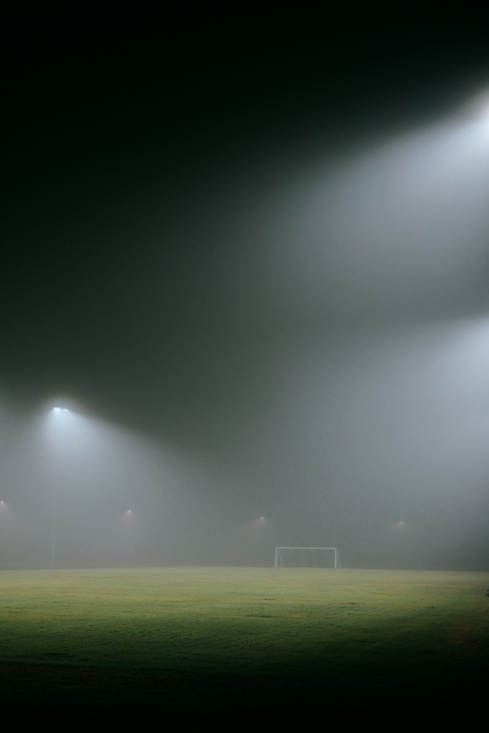 A foggy soccer field with three lights